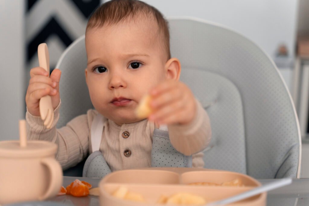 Baby self-feeding with finger foods during a baby-fed and spoon-fed weaning routine.