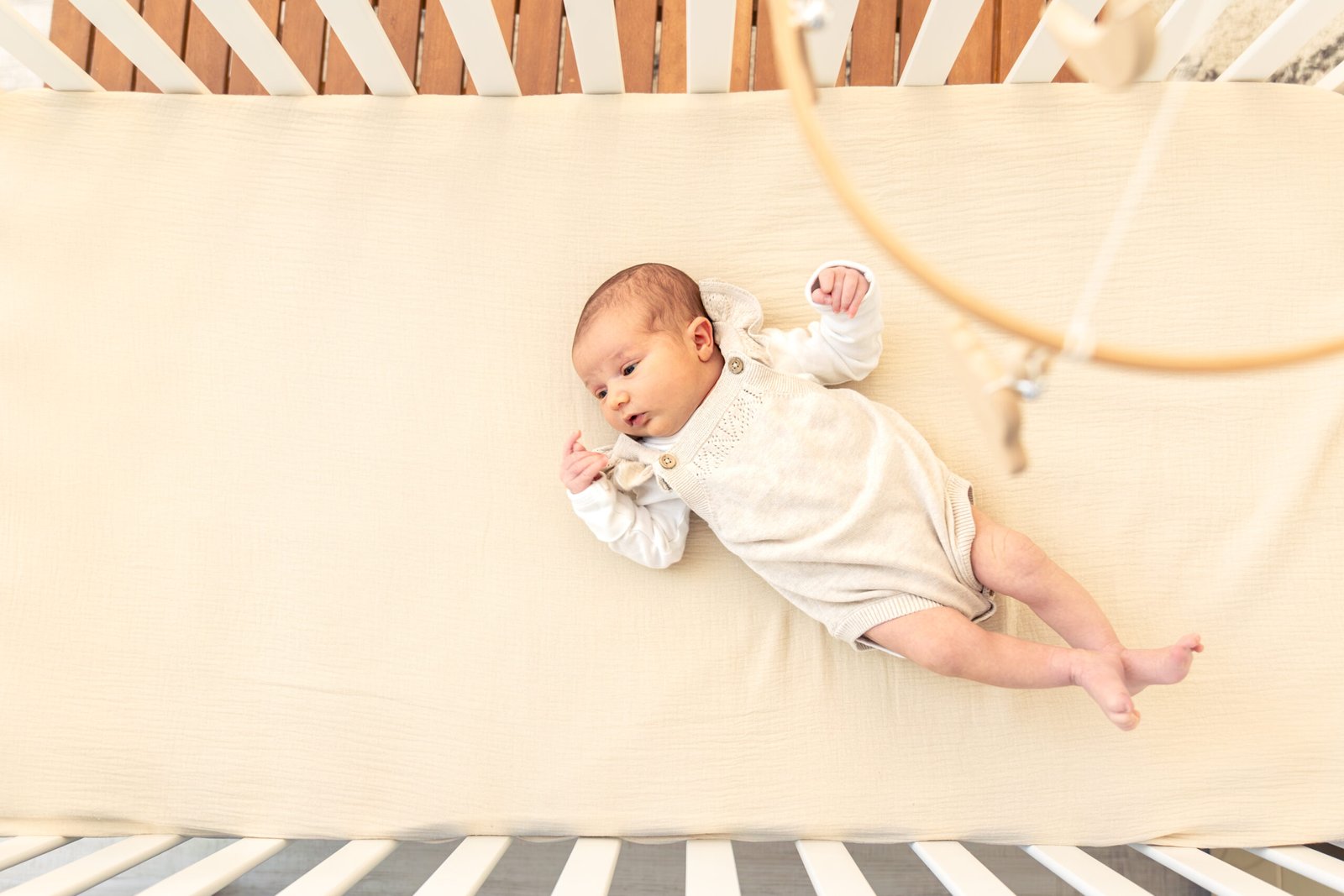Baby practising rolling over in a cot at night – baby rolling over tips for safer sleep during milestones.